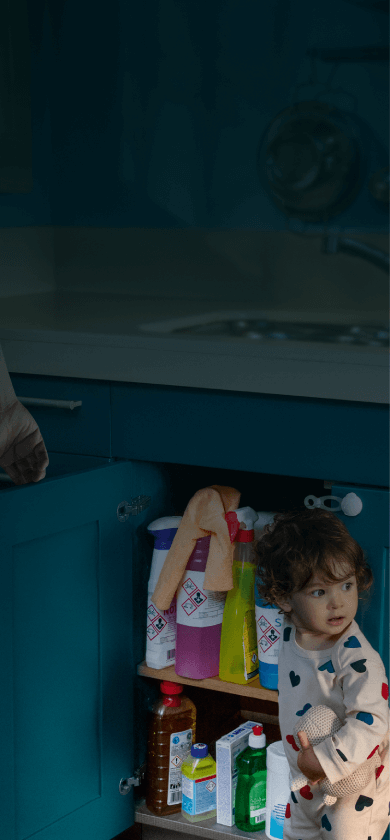Petit enfant debout près d'un placard de cuisine ouvert, dans une cuisine avec des armoires bleues, texte sur l'image.